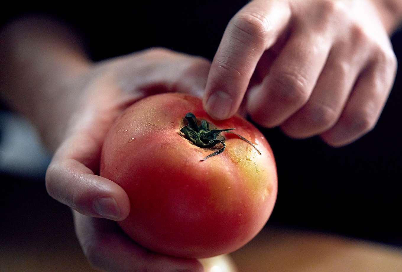 包丁の切っ先を、トマトのヘタのくぼみ始めのあたりに