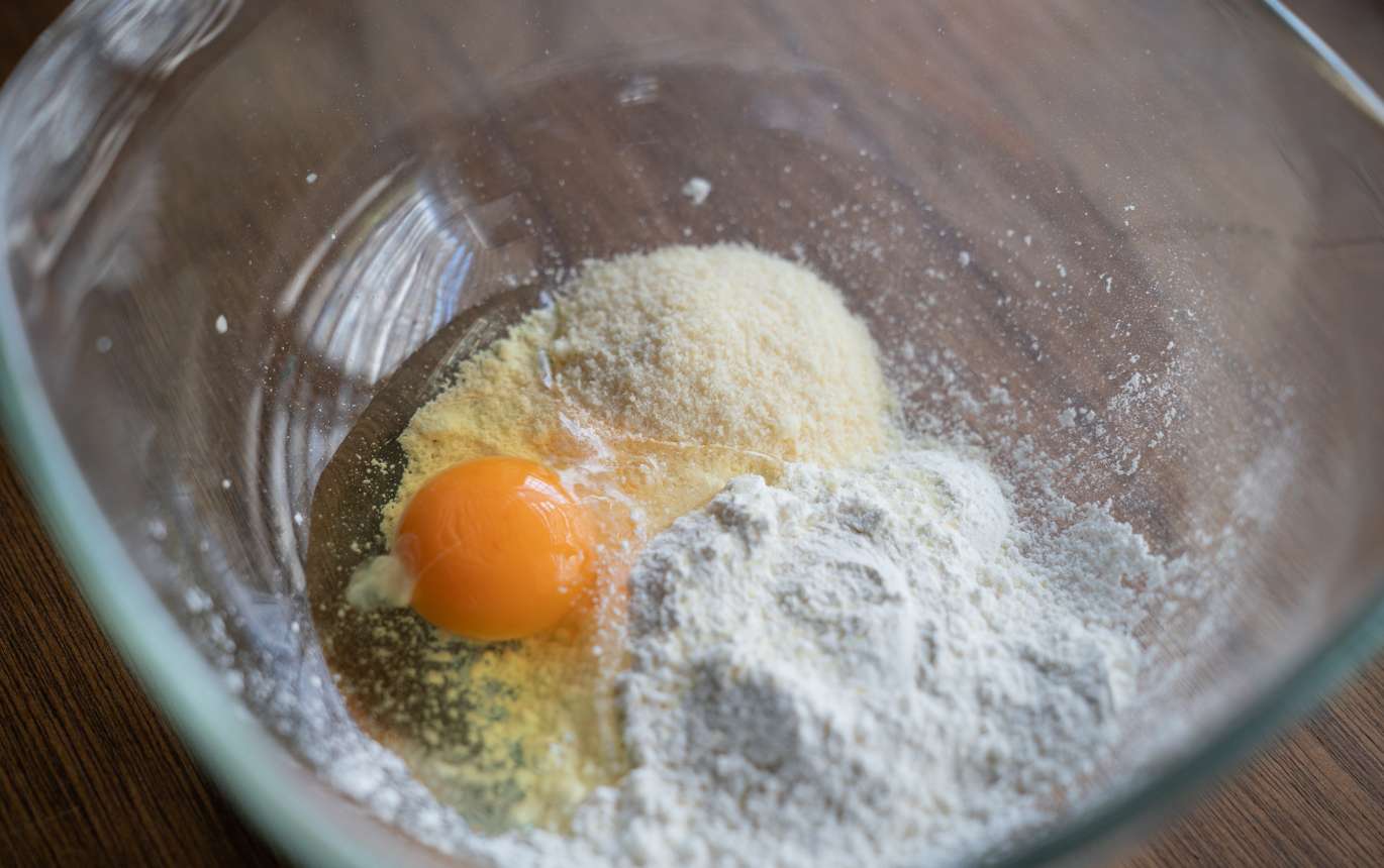ボウルに水と卵を入れて溶き、小麦粉、粉チーズを入れて混ぜ合わせる