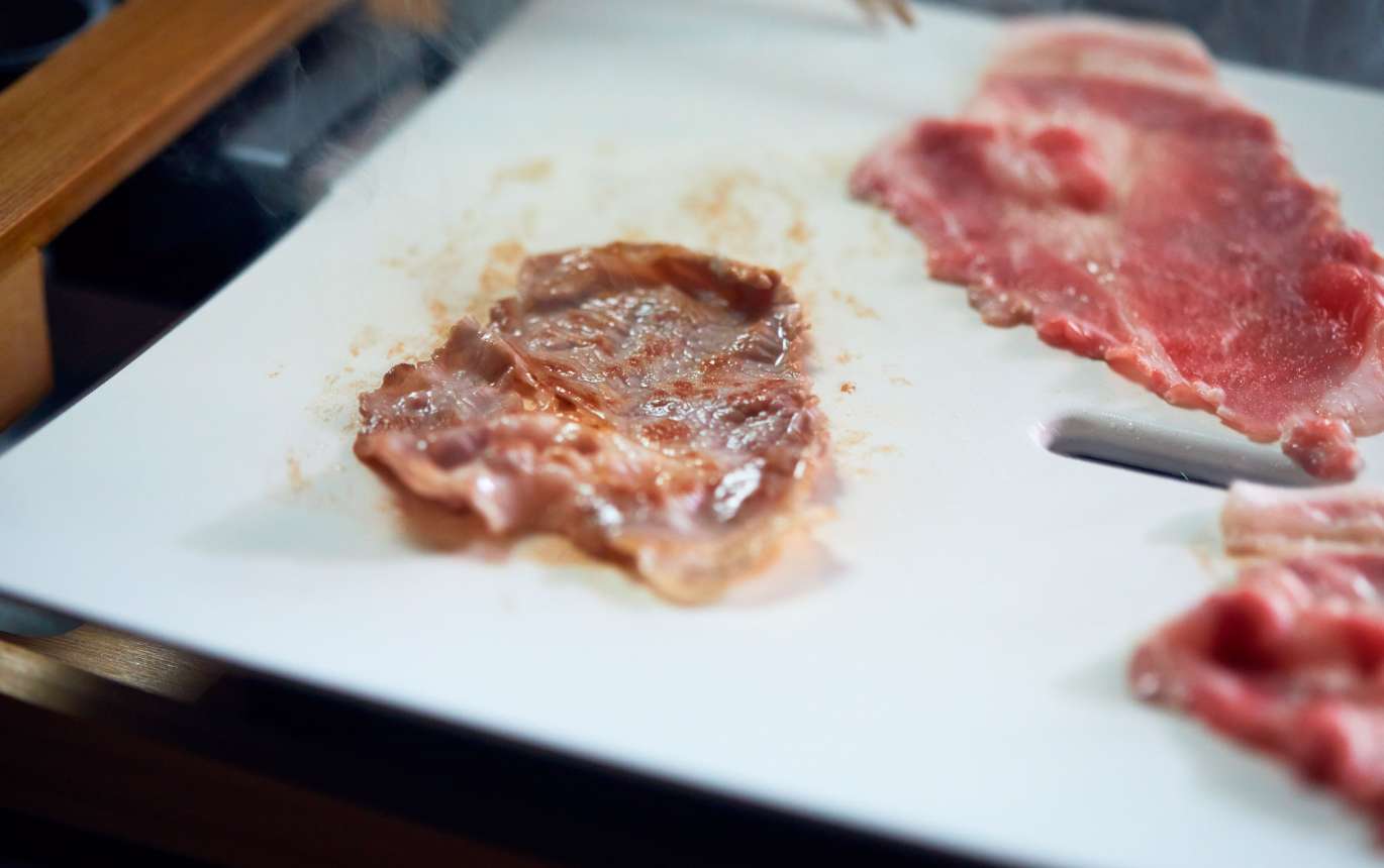 ホットプレートに米油を適量引き、170℃程度で熱する。豚肉を広げたら塩少々をふり、片面に焼き色をつける。